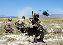 Airplane Picture - Pararescuemen and a simulated “survivor” watch as an HH-60G Pave Hawk helicopter comes in for a landing.