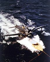 Airplane Picture - The USS Alaska (CB-1) recovering a SC-1 in March 1945, during the Iwo Jima operation. The aircraft is awaiting pickup by the ship's crane after taxiing onto a landing mat.