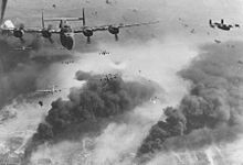 Airplane Picture - 15th Air Force B-24s fly through flak and over the destruction created by preceding waves of bombers.