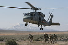 Helicopter Picture - A Seahawk waits above the ground to evacuate a simulated casualty as fellow MARSOC operators bring the Marine on a stretcher.