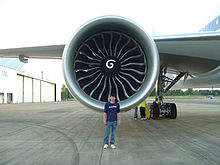 Airplane Picture - A GE90 engine mounted on a 777-300ER with a Boeing engineer to show the engine's size. Due to its size, the engine is capable of powering a Boeing 747 by itself.[74]