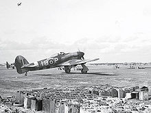 Airplane Picture - Late model Typhoon of 440(RCAF) Squadron. Note the bomb rack under the wing. Rows of five gallon jerrycans dominate the foreground