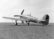 Airplane Picture - US-A was flown by Squadron Leader T.H.V Pheloung (Oamaru, New Zealand) April 1943.[41][nb 12] An 18-inch-wide (460 mm) yellow recognition stripe is visible on the upper wing.