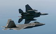 Airplane Pictures - An F-22 observes as an F-15 Eagle banks left. The F-22 is slated to replace the F-15C/D